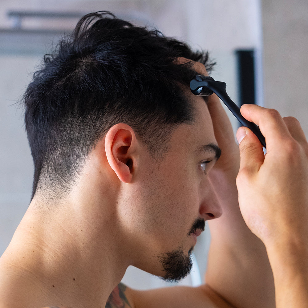 Man applying the ZENLUCA Hair Growth Dermaroller to his hairline in front of a mirror