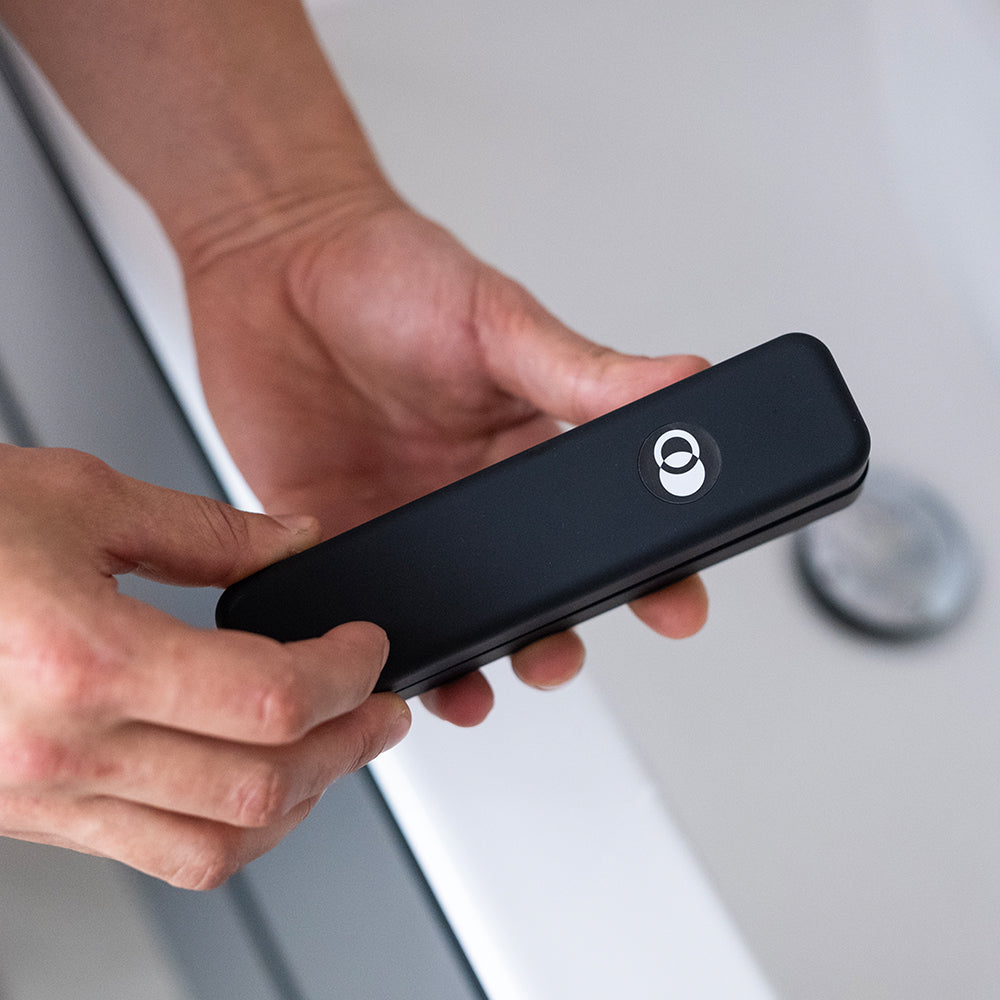 Person holding a ZENLUCA Hair Growth Dermaroller case in the bathroom