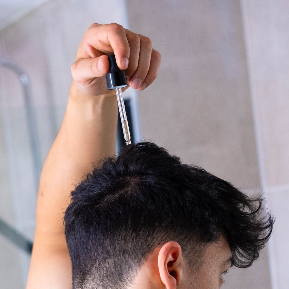 Man applying ZENLUCA Hair Growth Stimulating Serum with a dropper directly to the scalp