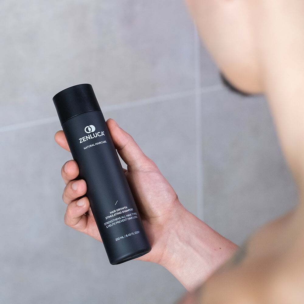 Person holding a bottle of ZENLUCA Hair Growth Stimulating Shampoo from the Signature Set